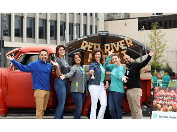 Group in front of Red River sign and red truck