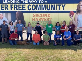 volunteers in front of a Second Harvest billboard