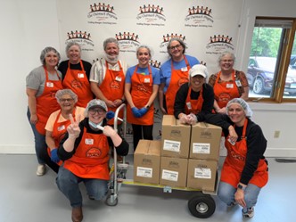 Group in red aprons and gathered around packages on a cart