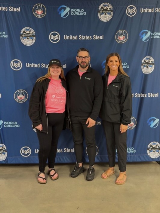 two women and a man in their midlle standing in front of a big banner